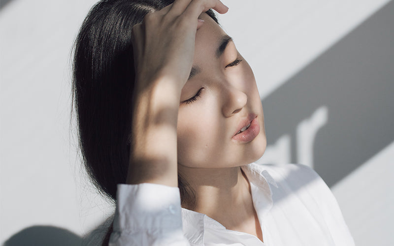 a woman in a white shirt is holding her head
