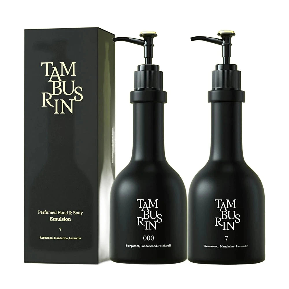 The image shows a set of TAMBURINS hand and body emulsion products. There are two black bottles with pumps labeled "000" and "7". The bottles are placed next to a black rectangular box with the brand name "TAMBURINS" written in gold lettering on it.